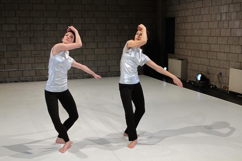 Hands frame the dancers' faces while their legs are in a plie